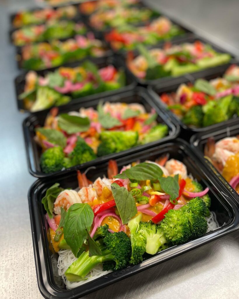 black plastic takeout containers filled with shrimp and vegetables