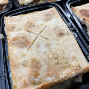 black plastic takout containers filled with slices of chicken pot pie