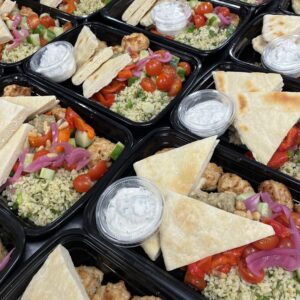 black takeout containers filled with bread, vegetables and meat