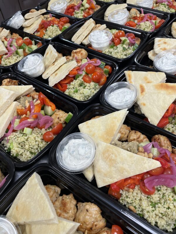 black takeout containers filled with bread, vegetables and meat